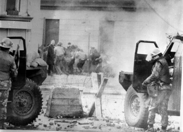 Soldiers take cover behind their sandbagged armoured cars while dispersing rioters with CS gas in Londonderry, on January 30 1972