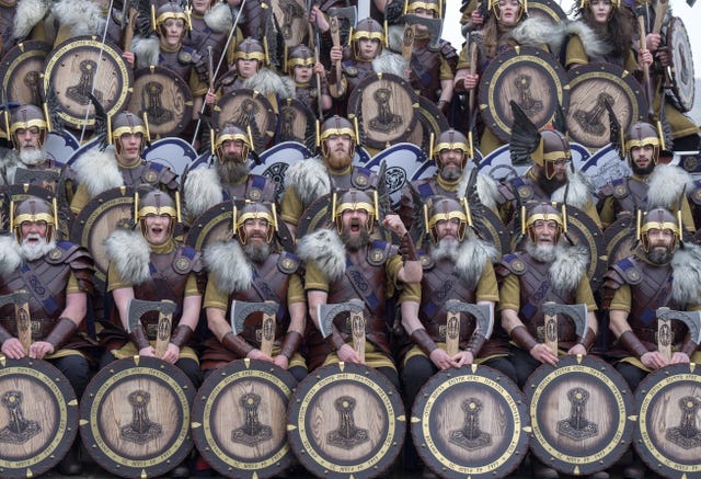 A group of men in Viking costume display their shields in formation