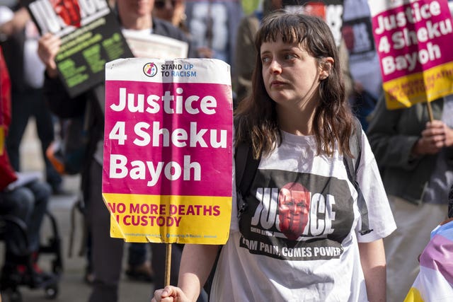 A woman holds a placard reading 'Justice 4 Sheku Bayoh'