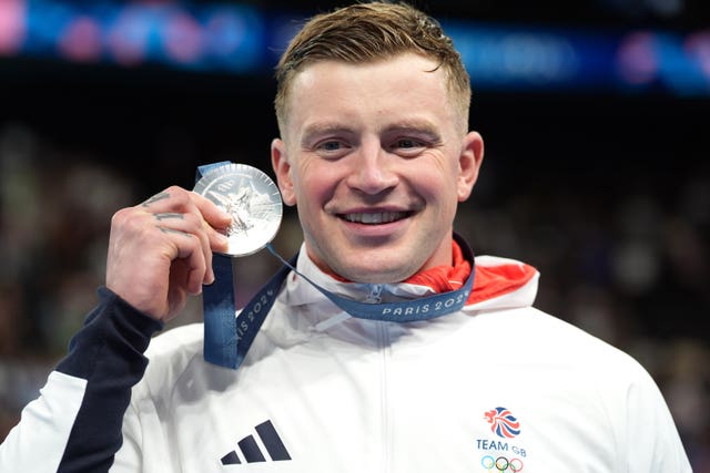 Adam Peaty celebrates with his Olympic silver medal held up to his face