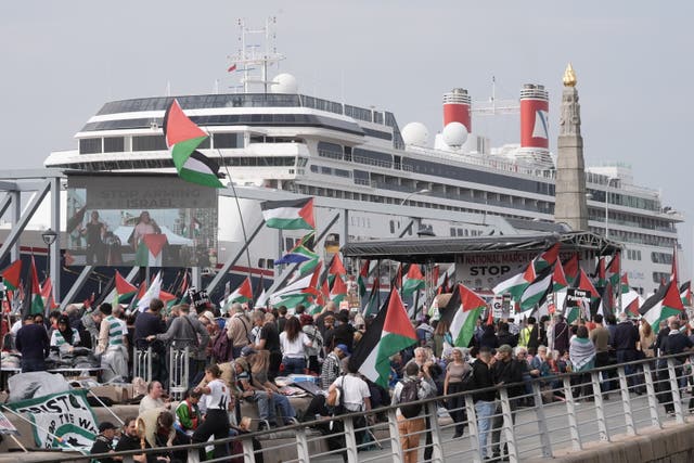 Crowds waving flags in front of a ship