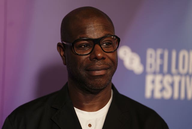 A close-up of Steve McQueen, wearing glasses