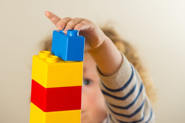 Preschool age child playing with plastic building blocks