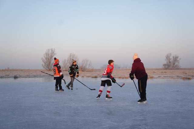 Skaters play ice hockey on a frozen field in Cambridgeshireh 2025