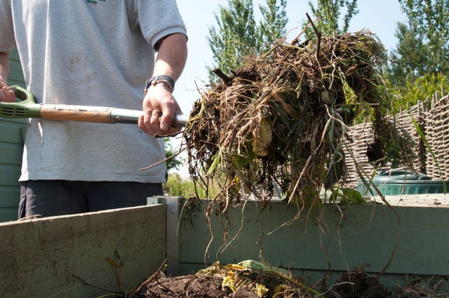 A gardener forking over their compost heap 