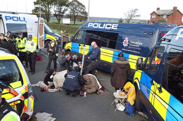 A police team cuts a man and woman out of a set of tyres, which they had apparently cemented their arms into, outside energy firm Cuadrilla’s site in Preston New Road