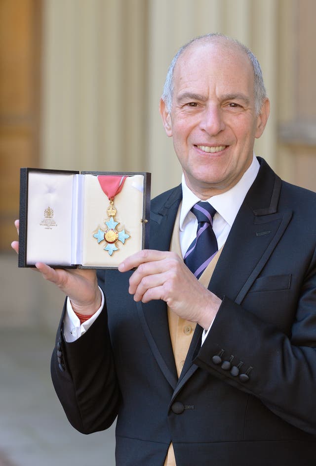 Loyd Grossman holds a medal after being made a CBE at Buckingham Palace