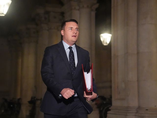 Health Secretary Wes Streeting walking along a street holding a folder