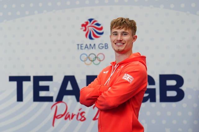 Jack Laugher with his arms crossed poses before a Team GB logo