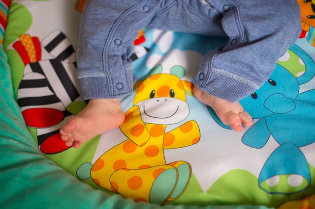 A baby's feet on a mat decorated with a giraffe, a zebra and an elephant