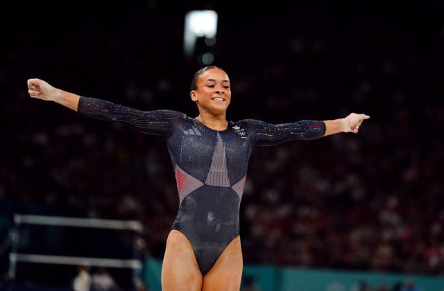 Becky Downie finishes a routine with her arms outstretched and a smile on her face.