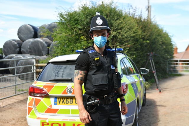 A police officer wears a face mask at Rook Row Farm in Mathon, near Malvern, Herefordshire, site of an outbreak of coronavirus (Jacob King/PA)
