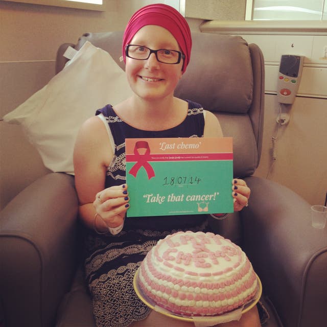 Jackie Scully sitting down wearing a headscarf with a cake on her lap and holding a certificate marking her last chemotherapy session