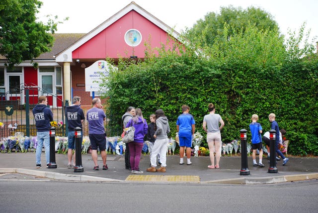 People look at the floral tributes at the entrance to Minehead Middle School in Somerset