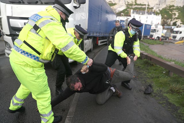 Police remove a man lying in the road in front a freight lorry as it tries to leave the Port of Dover 