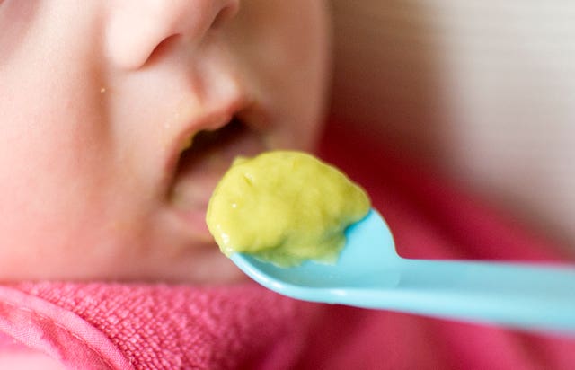 A baby eats puree from a spoon