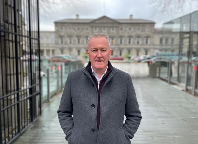 Conor Murphy poses for the camera in a grey coat