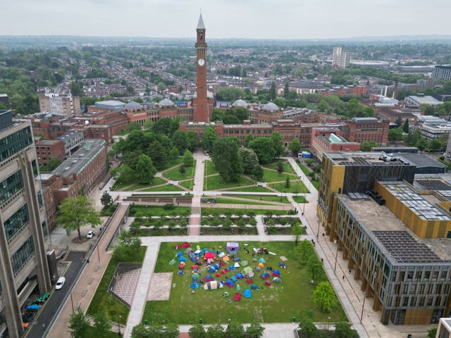 Aerial view of a sprawling university campus with a grassy section in the middle. There is a collection of brightly coloured tents on the largest open space