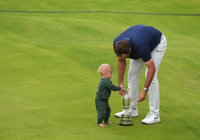 Scottie Scheffler and his son Bennett, left, celebrate victory with the Claret Jug on the 18th green at Royal Portrush