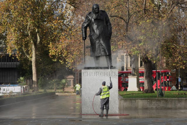 A workman uses a water jet spray to clean the statue of Sir Winston Churchill in Parliament Square