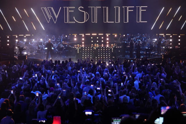 Westlife performing on stage, with a large crowd in front of them