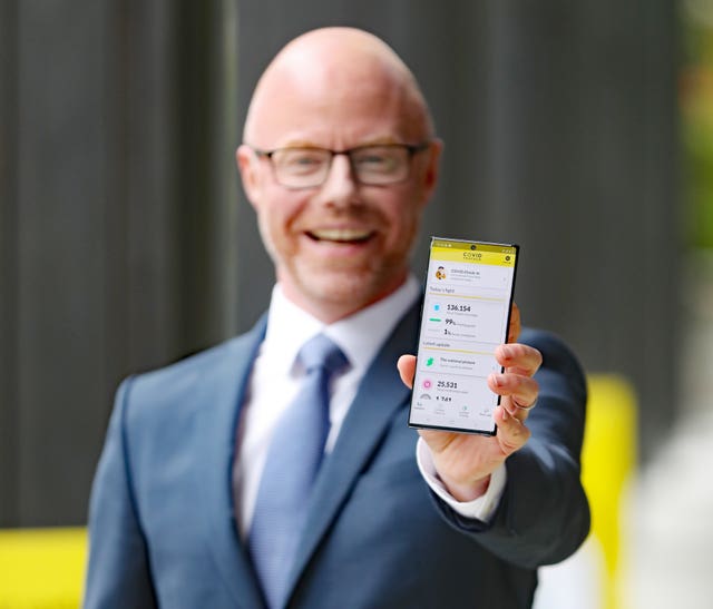 Stephen Donnelly holding a mobile phone showing Covid-19 data