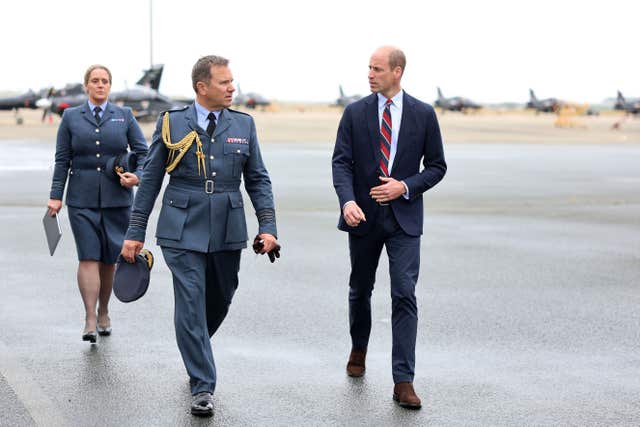 The Prince of Wales walks with an RAF officer on the tarmac