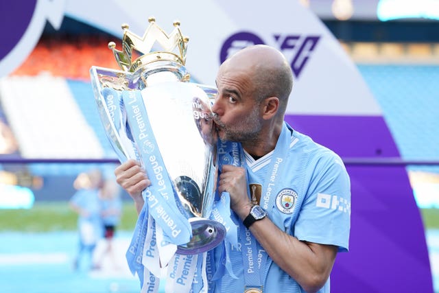 Pep Guardiola kisses the Premier League trophy