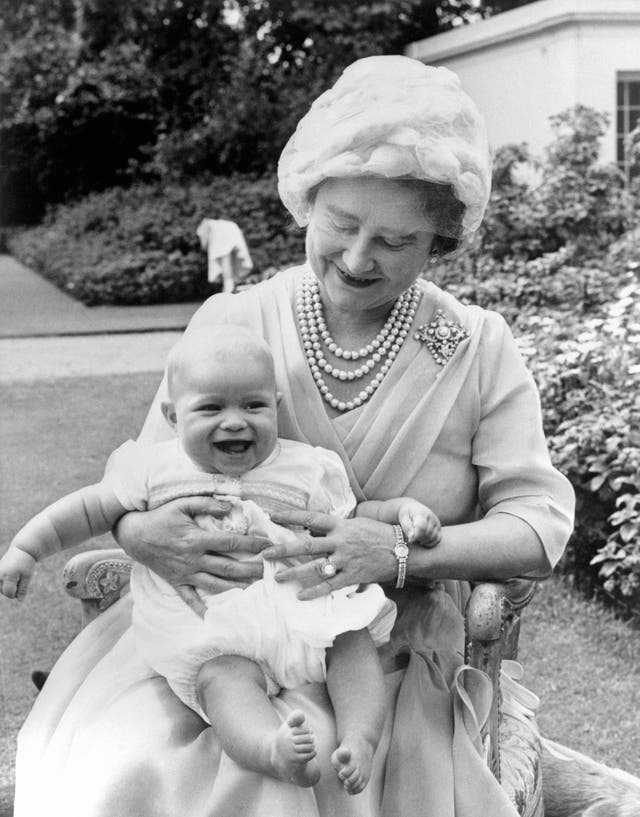 Prince Andrew chuckles with happiness on the knee of his grandmother, the Queen Mother, in the garden of Clarence House (PA)