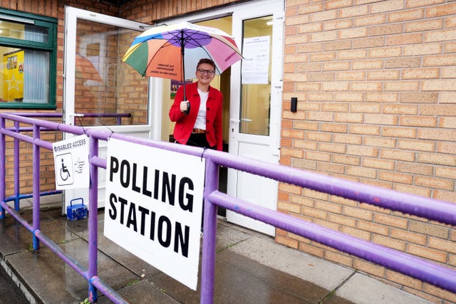 Bev Craig, carrying an umbrella, leaves a polling station in Didsbury
