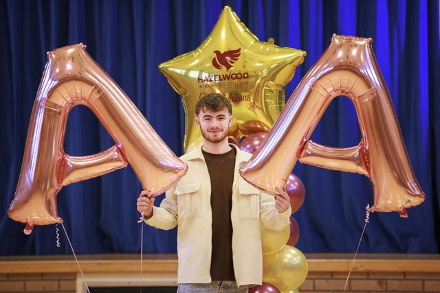 Shane Bunting who was awarded two As and a C in his A-level results holds two inflatable As in celebration at his college, Hazelwood Integrated in Newtonabbey, Belfast 