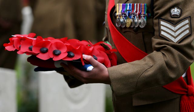A wreath is carried by a soldier during the burial service of two young privates and an unknown soldier, who fought during the First World War, at Hermies Hill British Cemetery, near Albert, France