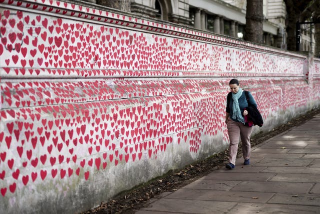 A person walking past the Covid victim's tribute wall in London