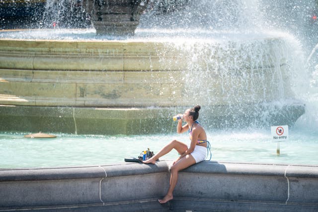 A woman sits by the fountains in Trafalgar Square, central London