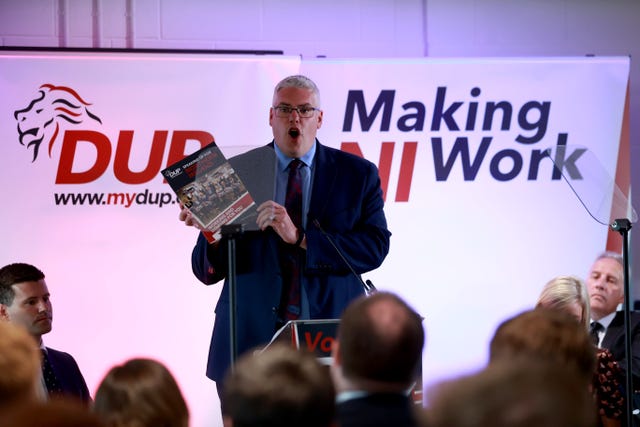 DUP leader Gavin Robinson holding a copy of the manifesto at a launch event