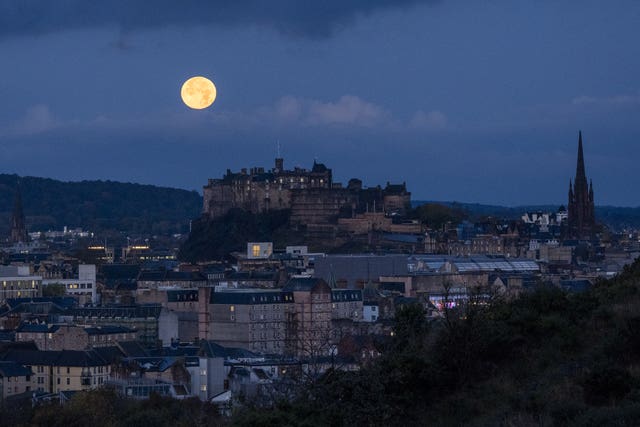 The full October moon, known as the Hunter’s, sets behind Edinburgh Castle