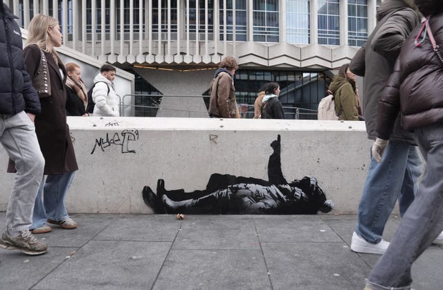 People walking past suspected Banksy artwork outside Centre Point building