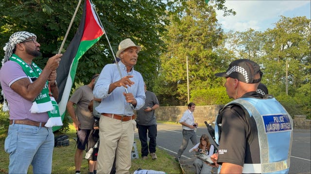 Police officers speak to protesters, some holding Palestinian flags, outside Carnell Estate in Ayrshire