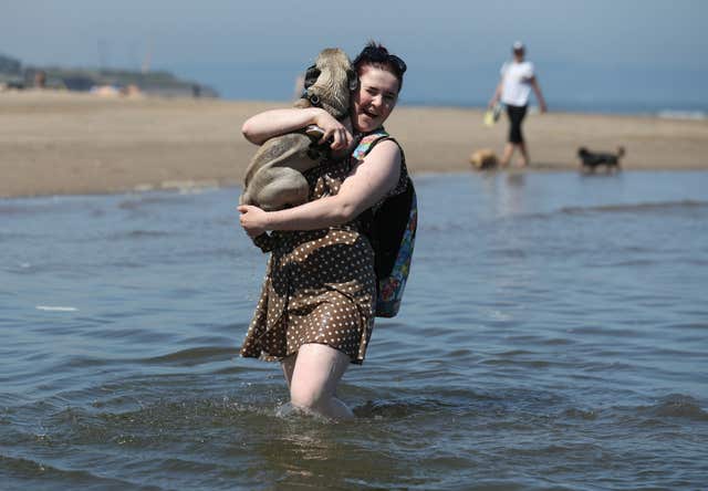 Norman the puggle gets a lift from owner Ashley Arthur after he took a dip in the sea at Portobello beach (Andrew Milligan/PA)