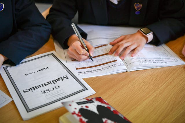 Students writing in a maths booklet 