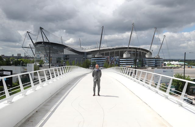 Manchester City manager Pep Guardiola poses in front of the Etihad Stadium at the City Football Academy