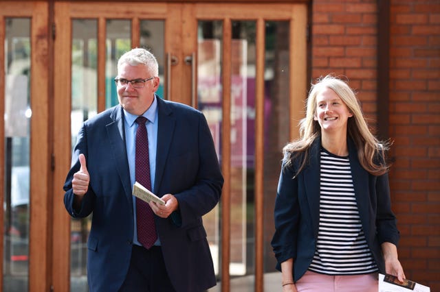 Gavin Robinson gives the thumbs up while walking with his wife Lindsay outside a polling station