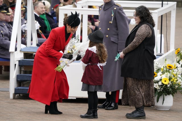 Kate is presented with a bouquet of flowers by a young girl in traditional Welsh costume