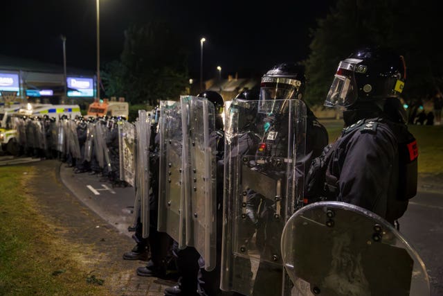 Officers from the PSNI form a barricade with riot shields