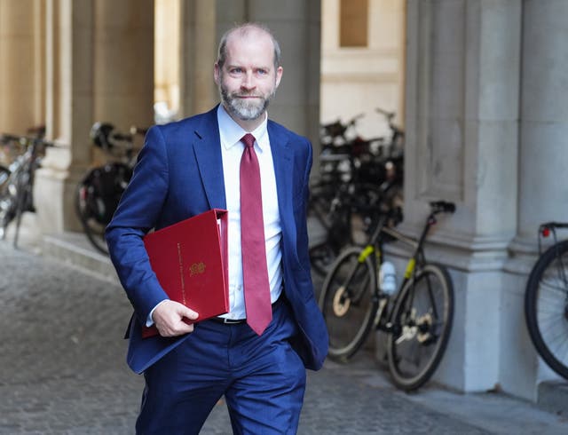 A man in a blue suit holding a red document folder