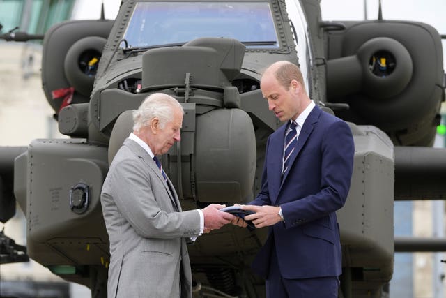 The King made the handover to the Prince of Wales in front of an Apache helicopter