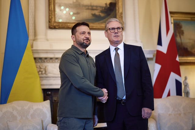 Two men shake hands with the Ukrainian flag and Union flag behind them