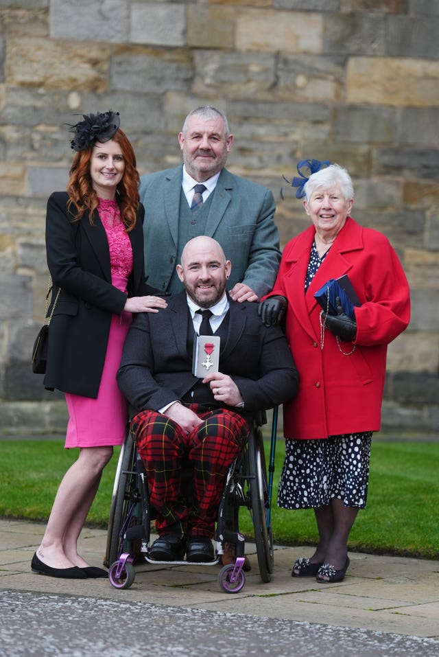 Nathan Macqueen holding a medal surrounded by members of his family