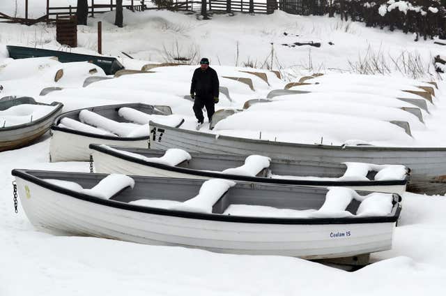 Jimmy Feeney from the Carron Valley Fishery inspects his snow covered boats near Stirling, following the recent severe weather (Andrew Milligan/PA)