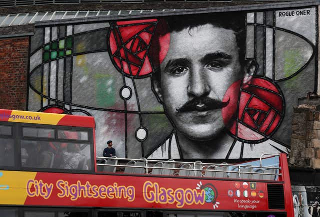 A tour bus passes in front of the new mural dedicated to Charles Rennie Mackintosh on a large wall overlooking the Clutha bar in Glasgow (Andrew Milligan/PA)